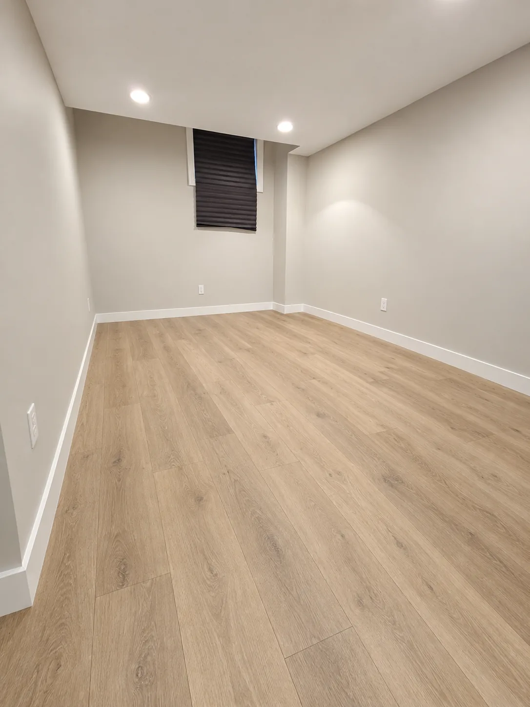 Restored basement room in Noblesville, IN with finished walls, trim and new plank flooring
