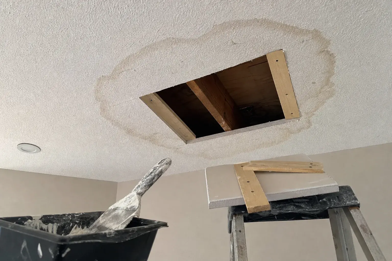 Water-stained ceiling drywall cut back to the framing before repair in Noblesville, IN