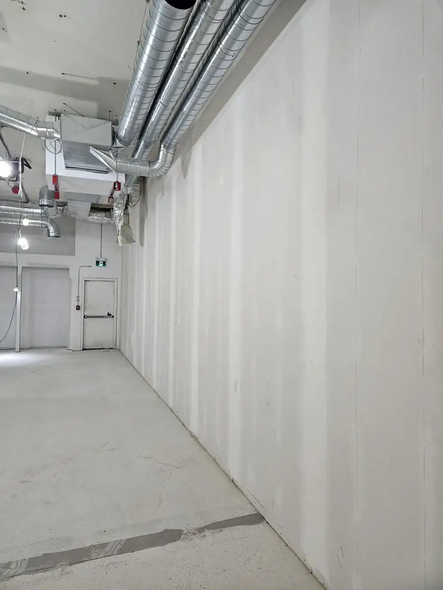 Long finished commercial corridor wall with exposed ductwork above during commercial construction in Noblesville, IN