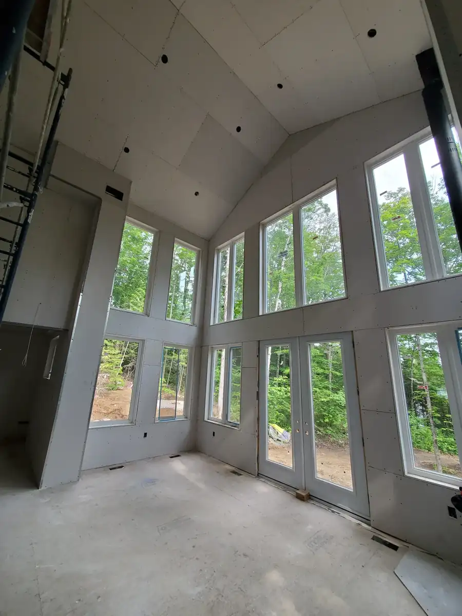 Interior of a Noblesville, IN custom home with drywall hung on vaulted ceilings and tall window walls
