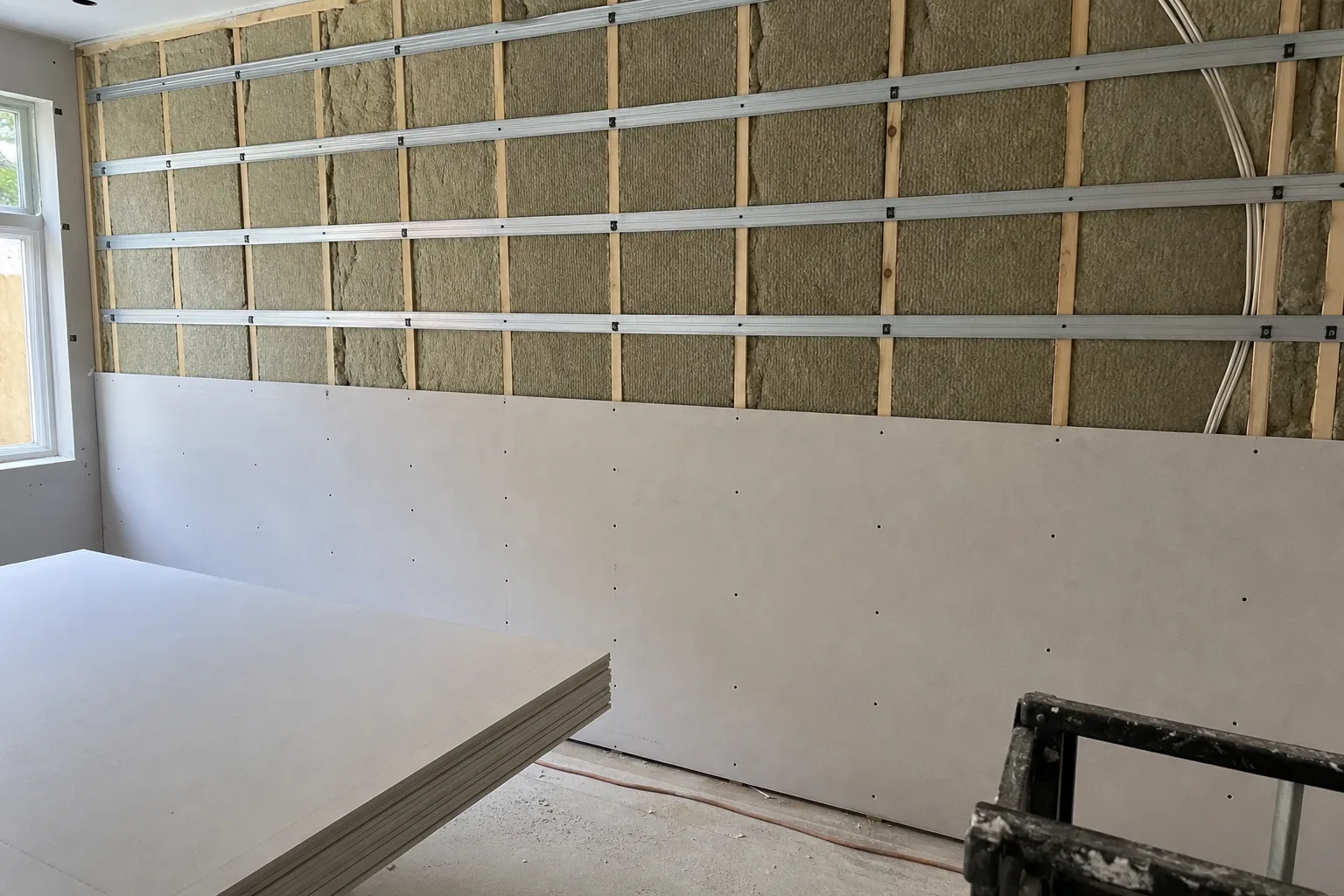 Party wall with mineral wool and resilient channel before sound-rated drywall in Noblesville, IN