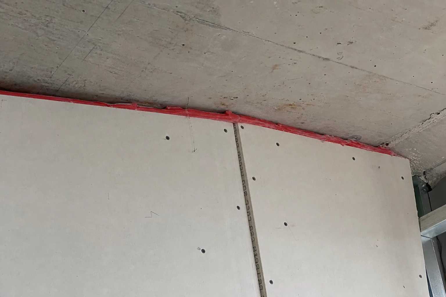Type X drywall partition with red fire-stop sealant at the head-of-wall joint in a Noblesville, IN building